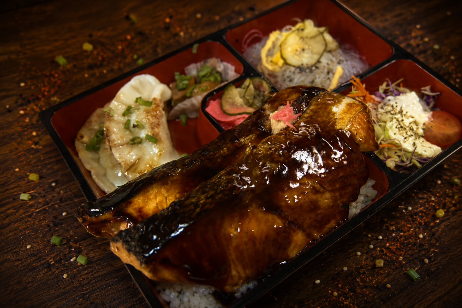 Bento de salmón teriyaki con gyozas, ensalada y arroz